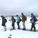 Researchers walk across the snowy tundra.